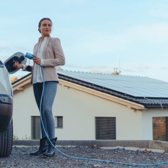 Young woman charging electric car in home, sustainable and economic transportation concept.